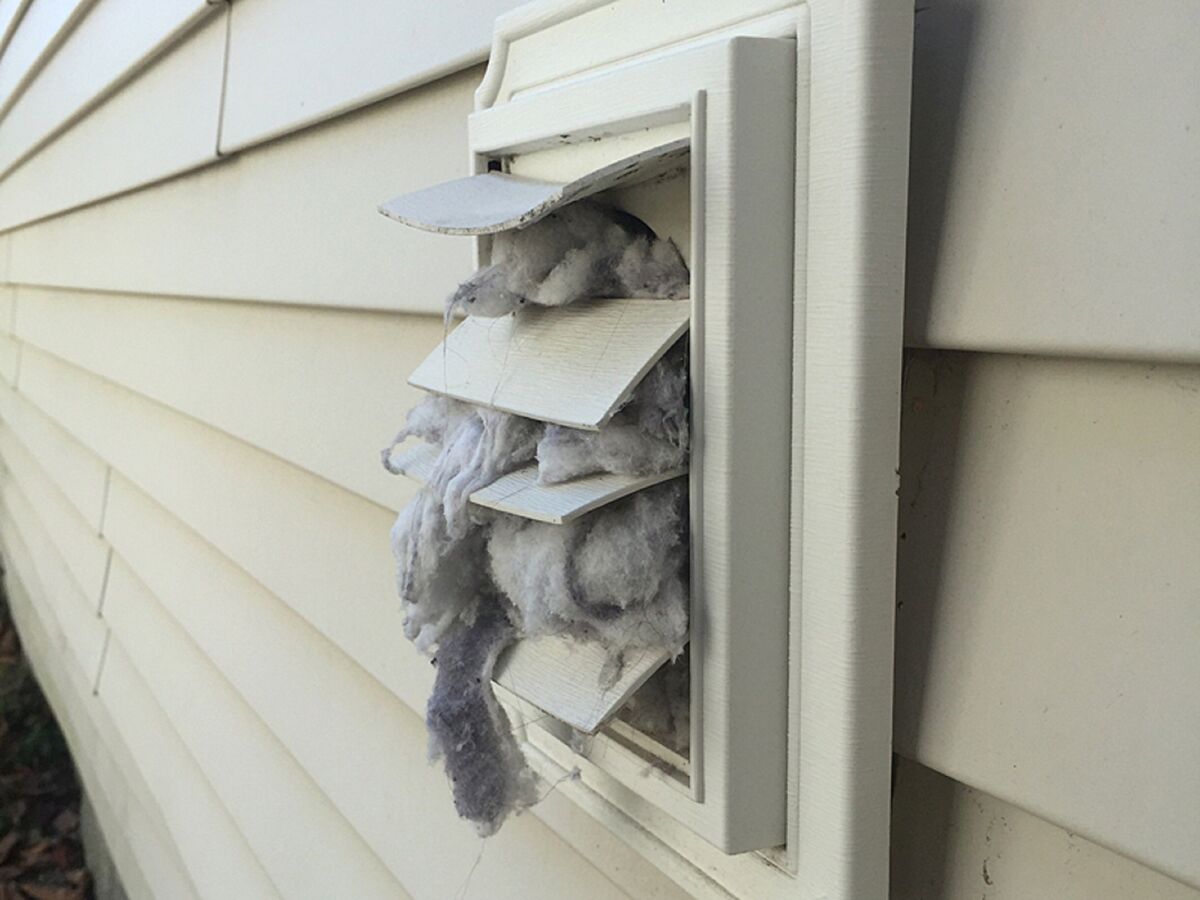 Dryer vent cap on vinyl siding overflowing with lint